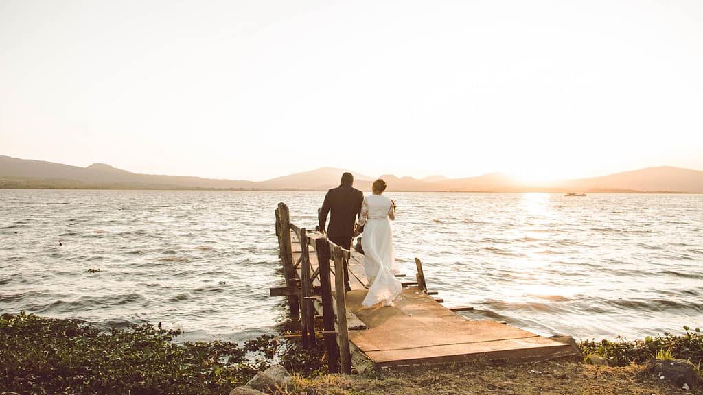 couple standing on wooden dock by the sea during daytime