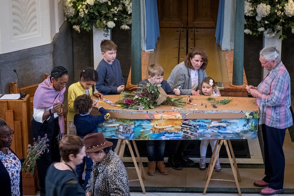 a group of people standing around decorating a coffin