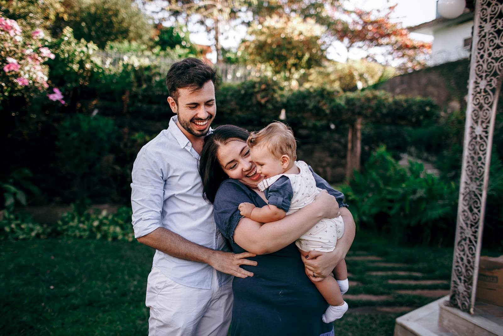 A joyful family moment with parents and baby embracing in a vibrant garden.