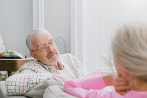 Elderly couple in conversation indoors; relaxed and intimate setting.