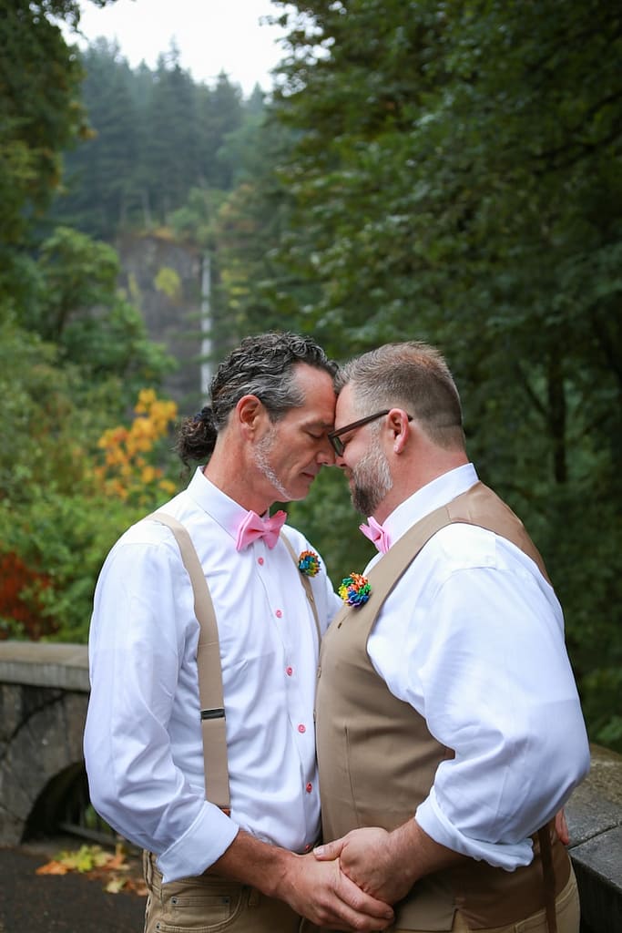a couple of men foreheads touching surrounded by woodland