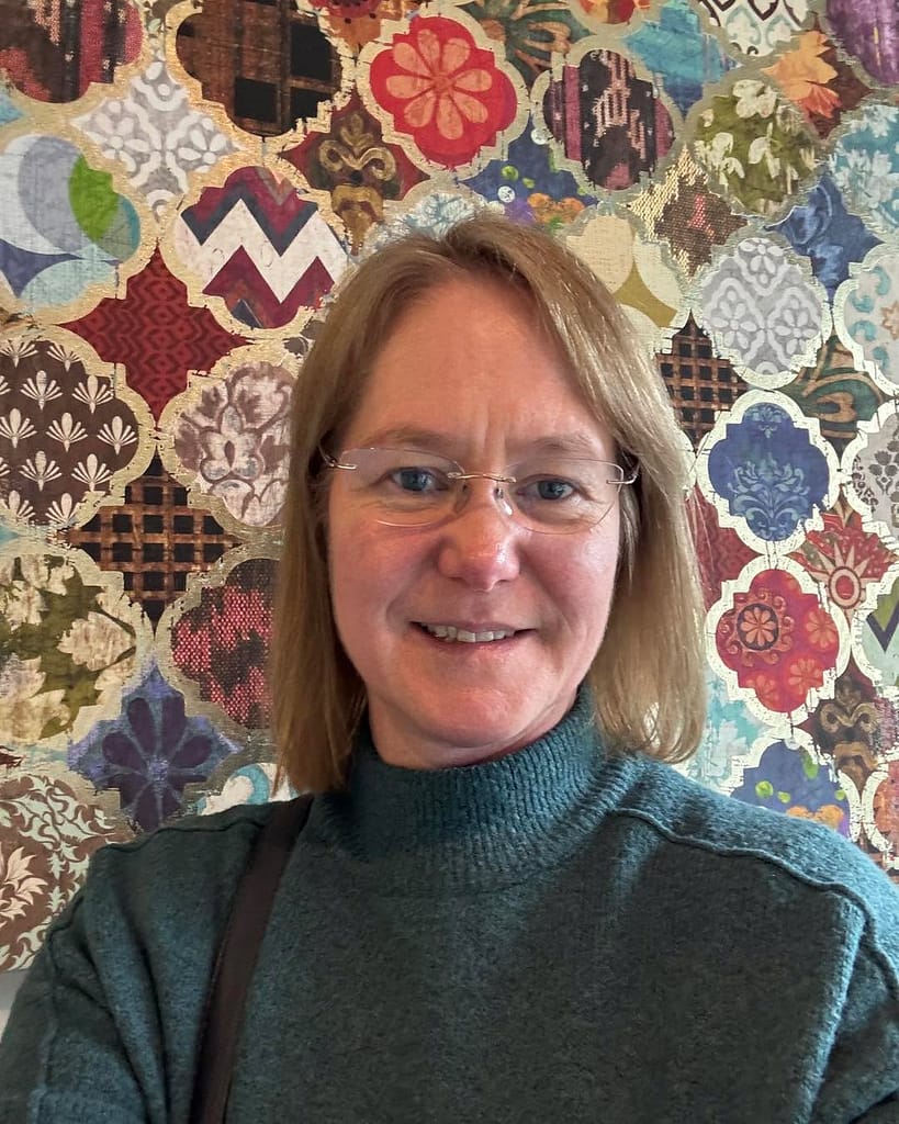 Fleur standing in front of a multi-colour mosaic wall