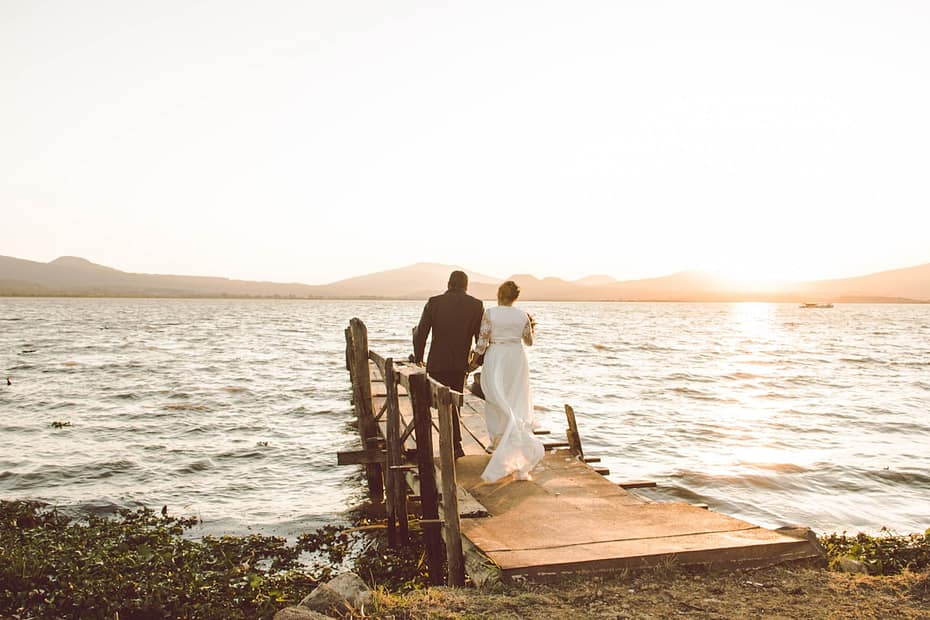 couple standing on wooden dock by the sea during daytime